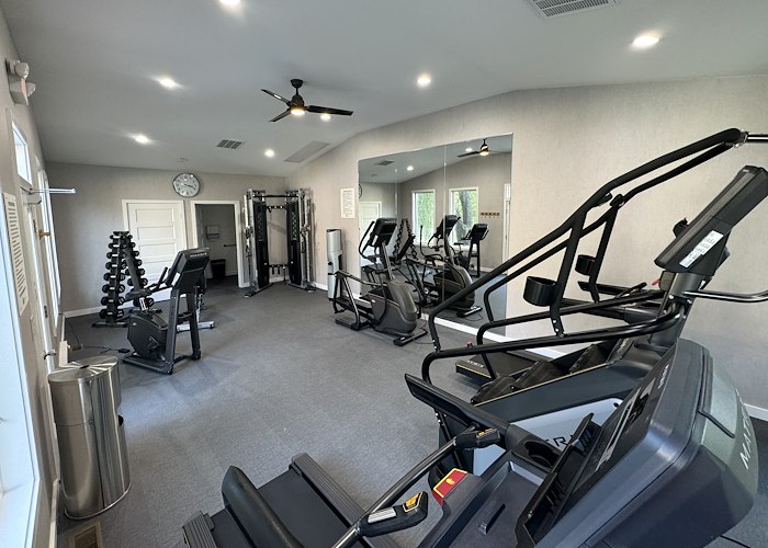 A gym room with exercise equipment and a ceiling fan at California Apartments in Absecon, New Jersey