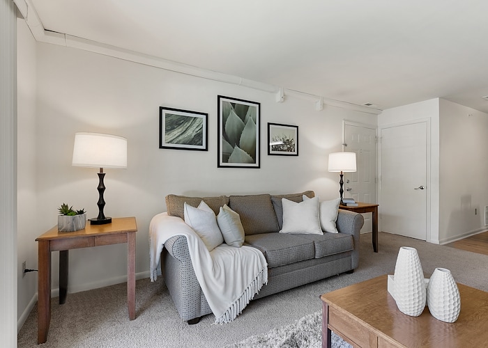 A living room with a couch, coffee table and two lamps at California Apartments in Absecon, New Jersey