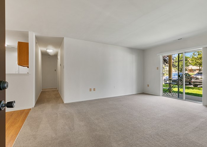 An empty room with a sliding glass door at California Apartments in Absecon, New Jersey