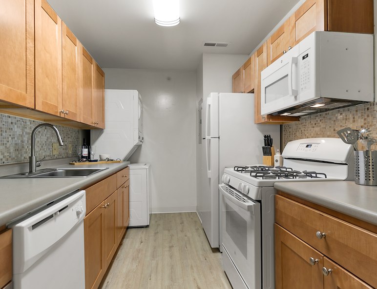 Modern kitchen in California Furnished Apartments, featuring wood cabinets, appliances, and a sleek countertop