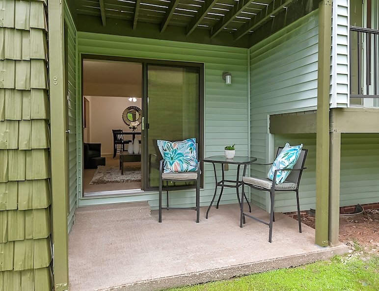 A patio with a table and chairs in front of a green house, Country Club Apartments, Huntington, West Virginia