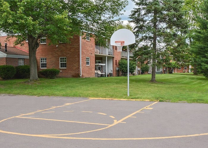 A basketball court in front of a building with trees at Gateway Apartments in Edwardsville, Pennsylvania