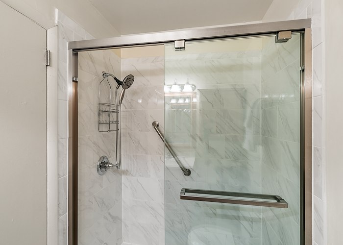 A glass shower door with a shower head and a toilet at Gateway Apartments in Edwardsville, Pennsylvania