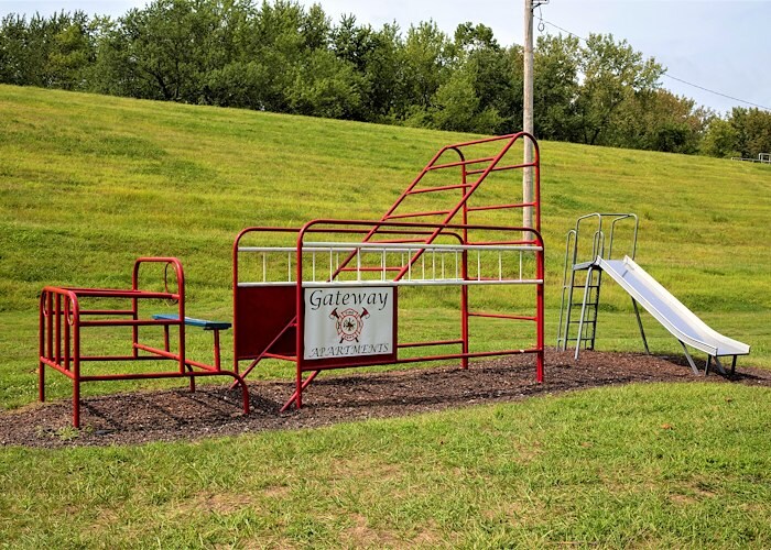 A red playground set with a slide and a fence at Gateway Apartments in Edwardsville, Pennsylvania