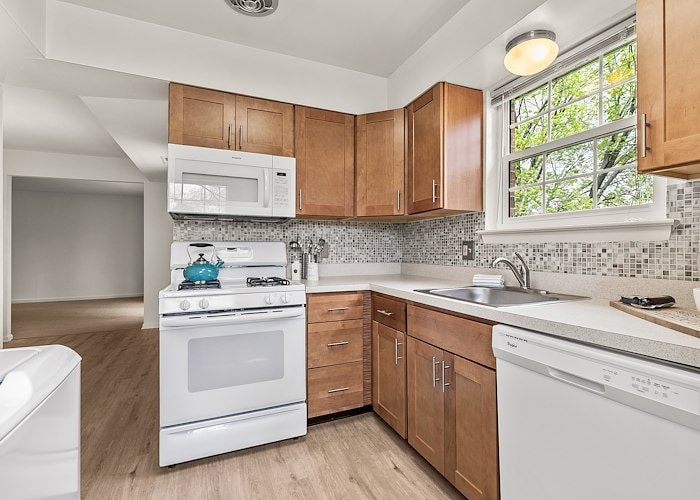 A kitchen with white appliances and wood cabinets at Gateway Apartments in Edwardsville, Pennsylvania