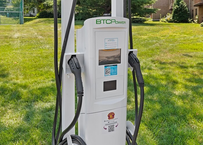 A white electric vehicle charging in the grass, Grampian Hills Apartments, Williamsport, Pennsylvania