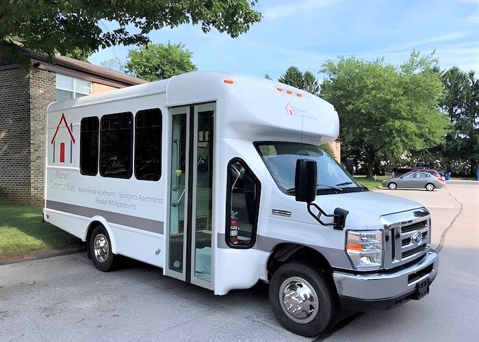 A white bus with a door open on the side of the road, Manor House Apartments, Lancaster, Pennsylvania