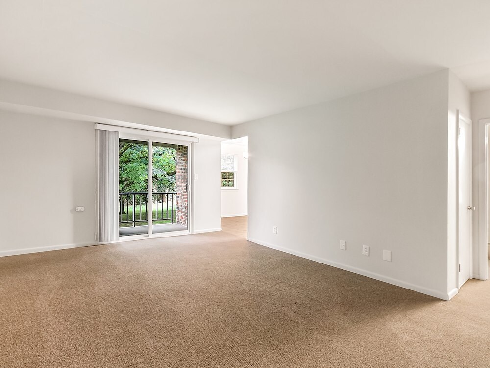 Spacious one-bedroom living room at Manor House Apartments featuring sliding-glass doors that lead to a private patio or balcony.