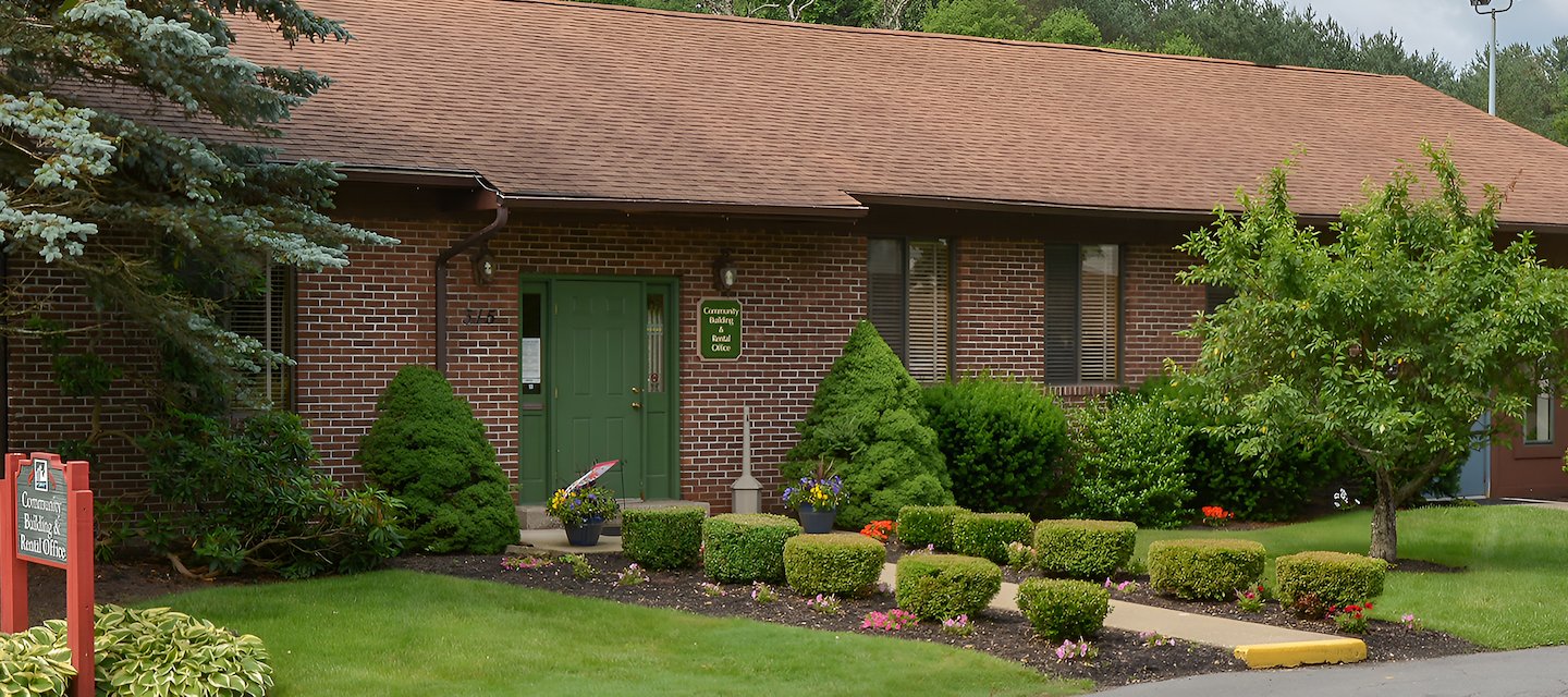A small brick building with a green door and a sign at Pikeview Manor Apartments in Beckley, West Virginia