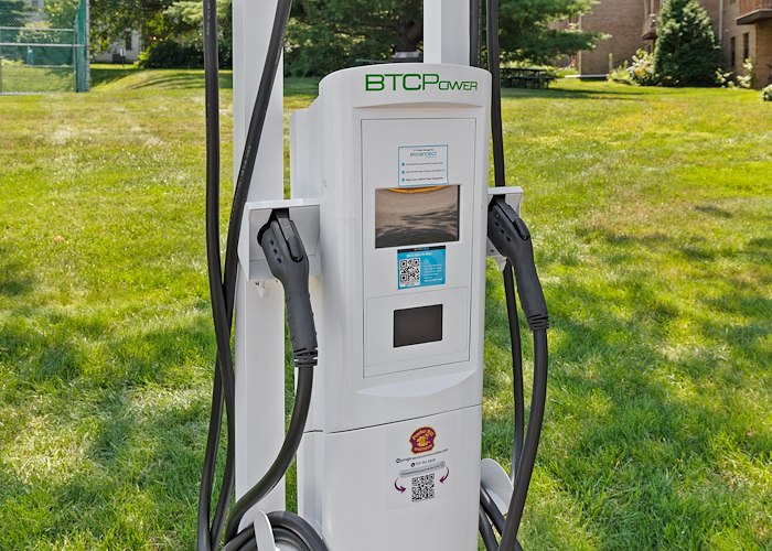 A white electric vehicle charging in the grass, Powder Mill Apartments, York, Pennsylvania