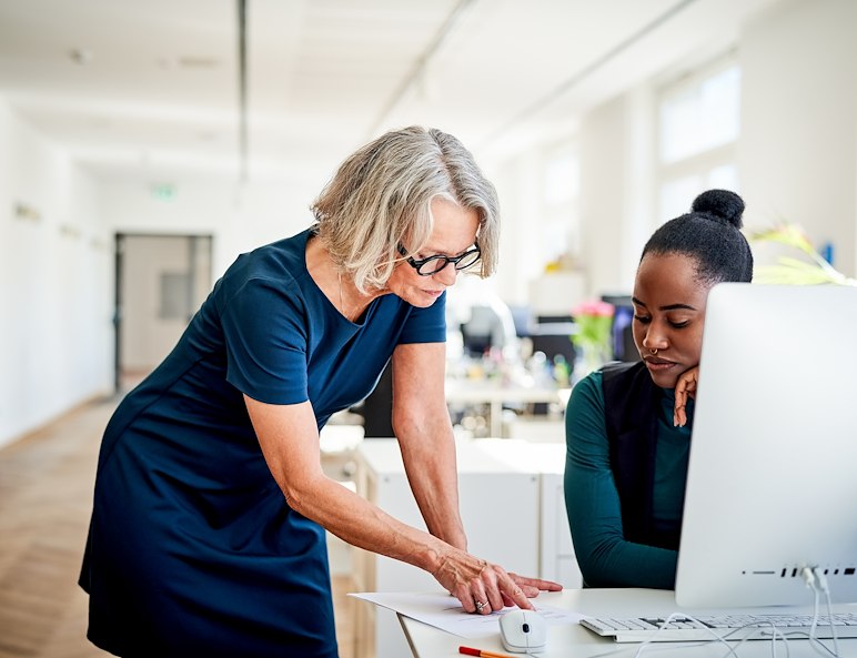 Two women collaborate at a desk in a bright office, embodying the teamwork spirit of Manor Communities in Lancaster