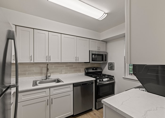 A kitchen with white cabinets and stainless steel appliances at Springetts Apartments in York, Pennsylvania