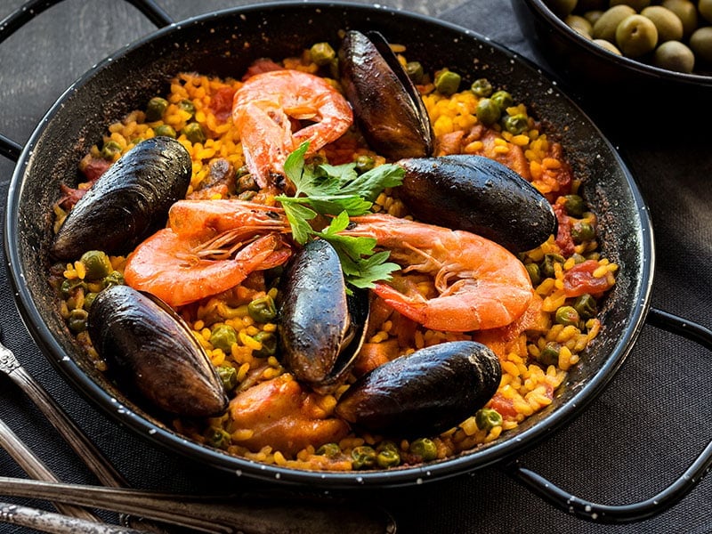 a seafood paella dish with shrimp, mussels, and vegetables