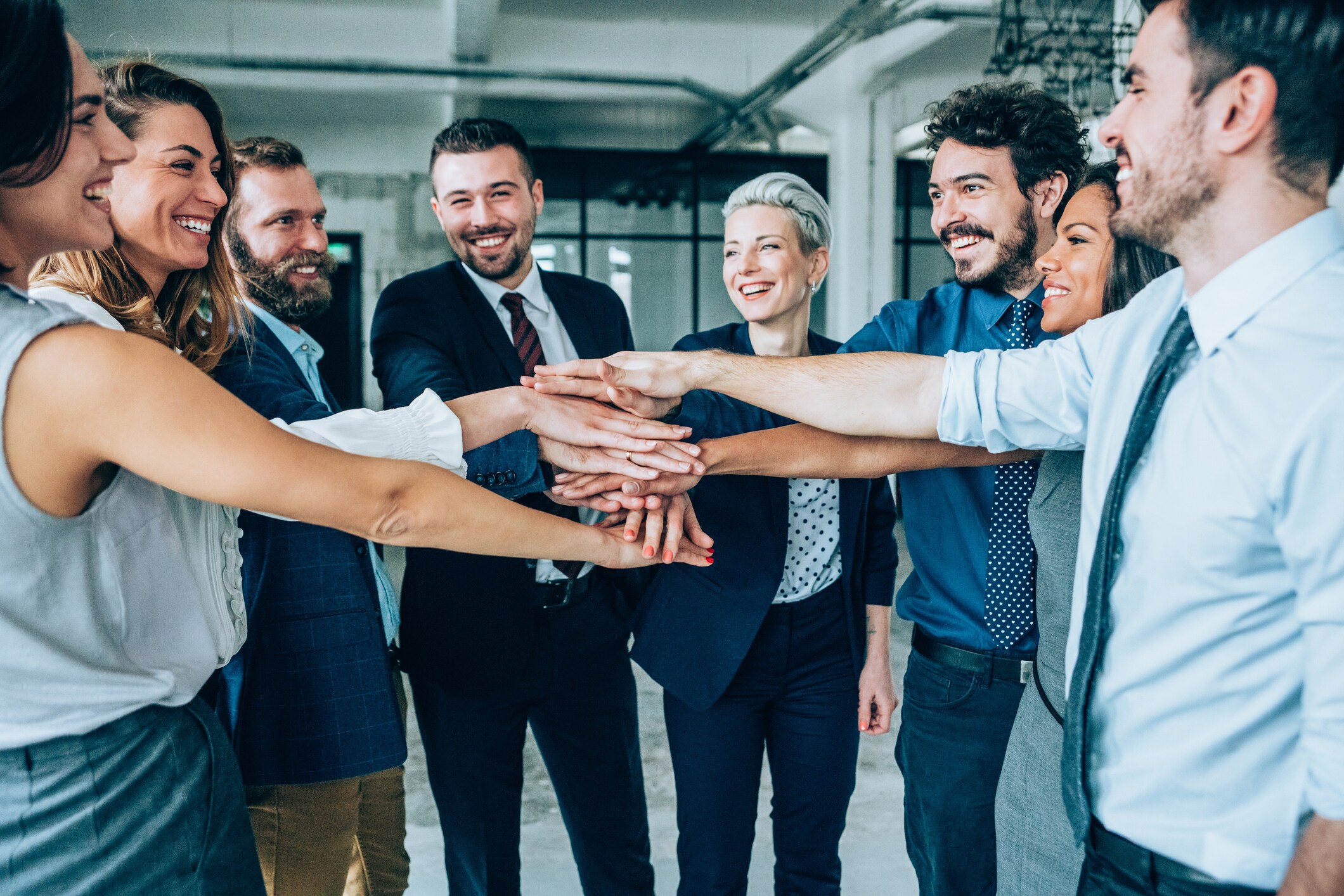 Group of business people with stacked hands showing unity and teamwork