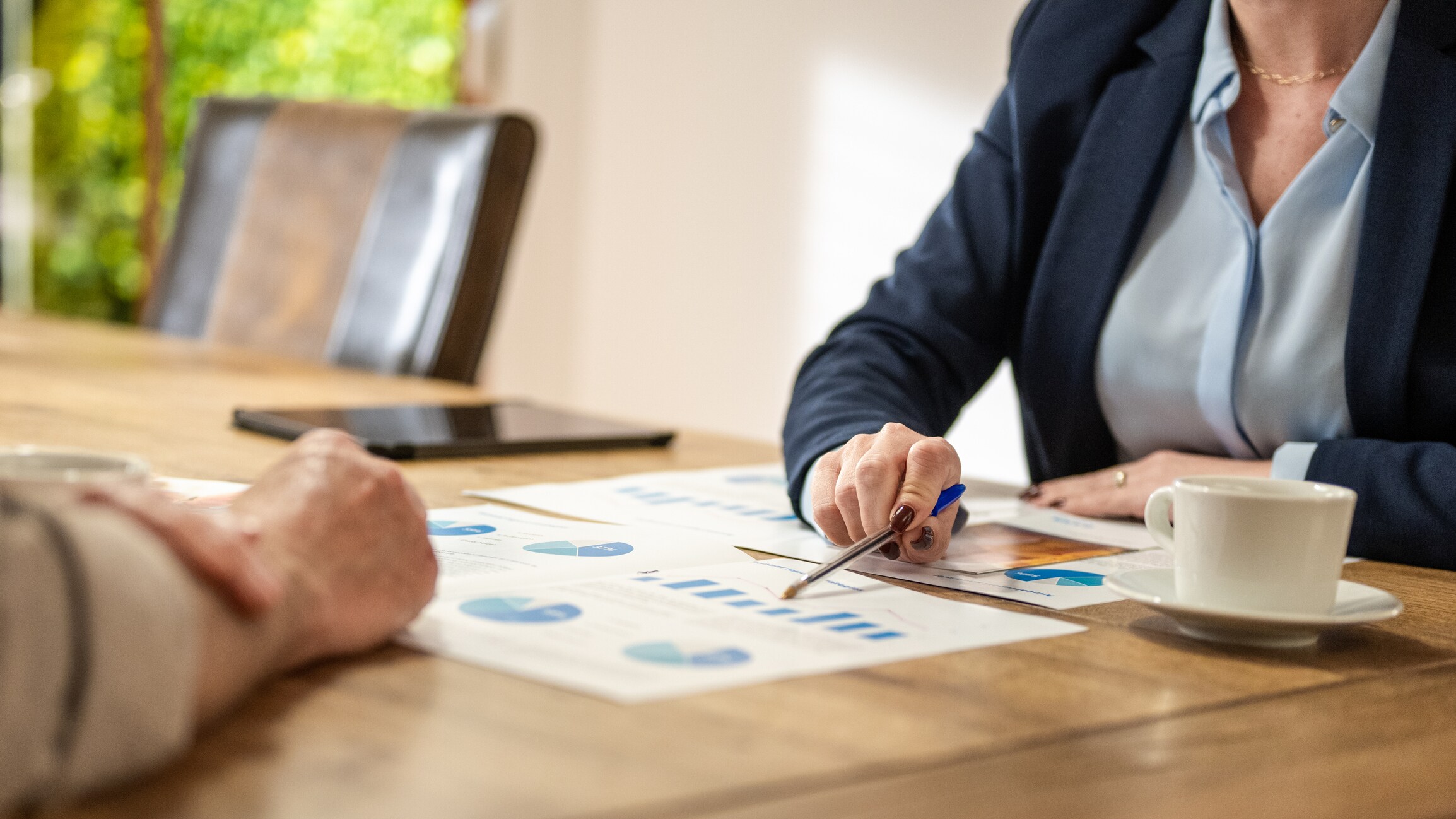Mid section of financial advisor presents chart to client at table.