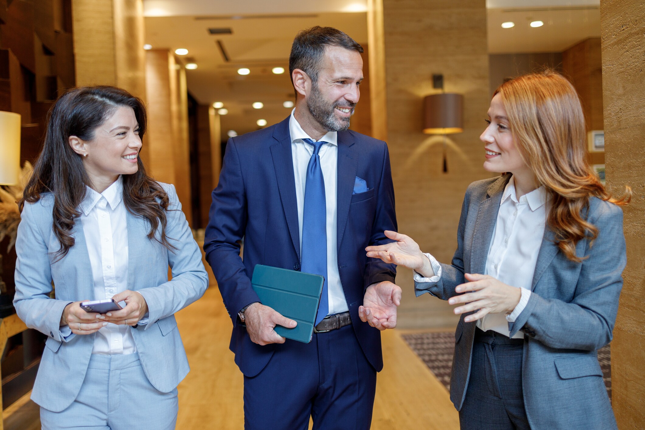 Three business people walking and talking engaging in a professional discussion.