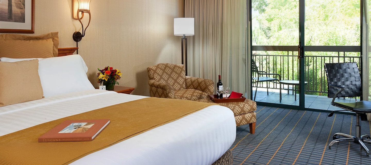 Cozy room at Creekside Inn, Palo Alto, featuring comfy seating and balcony view.