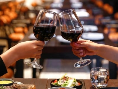 Two people clinking wine glasses over a table with food