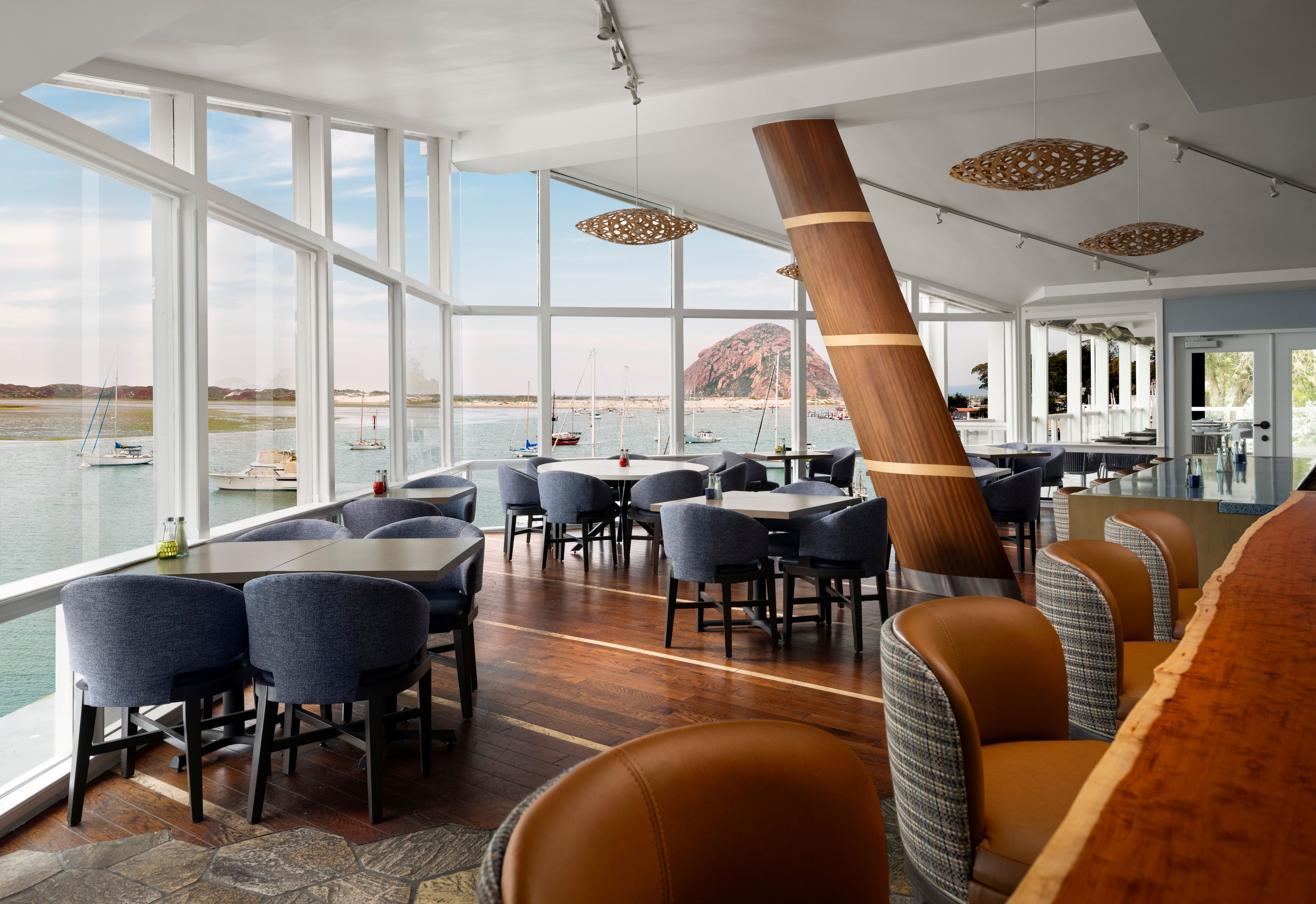 A dining area with large windows overlooking the water and a mountain in the distance.