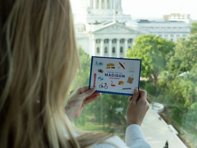 A woman holding a card with a white building in the background