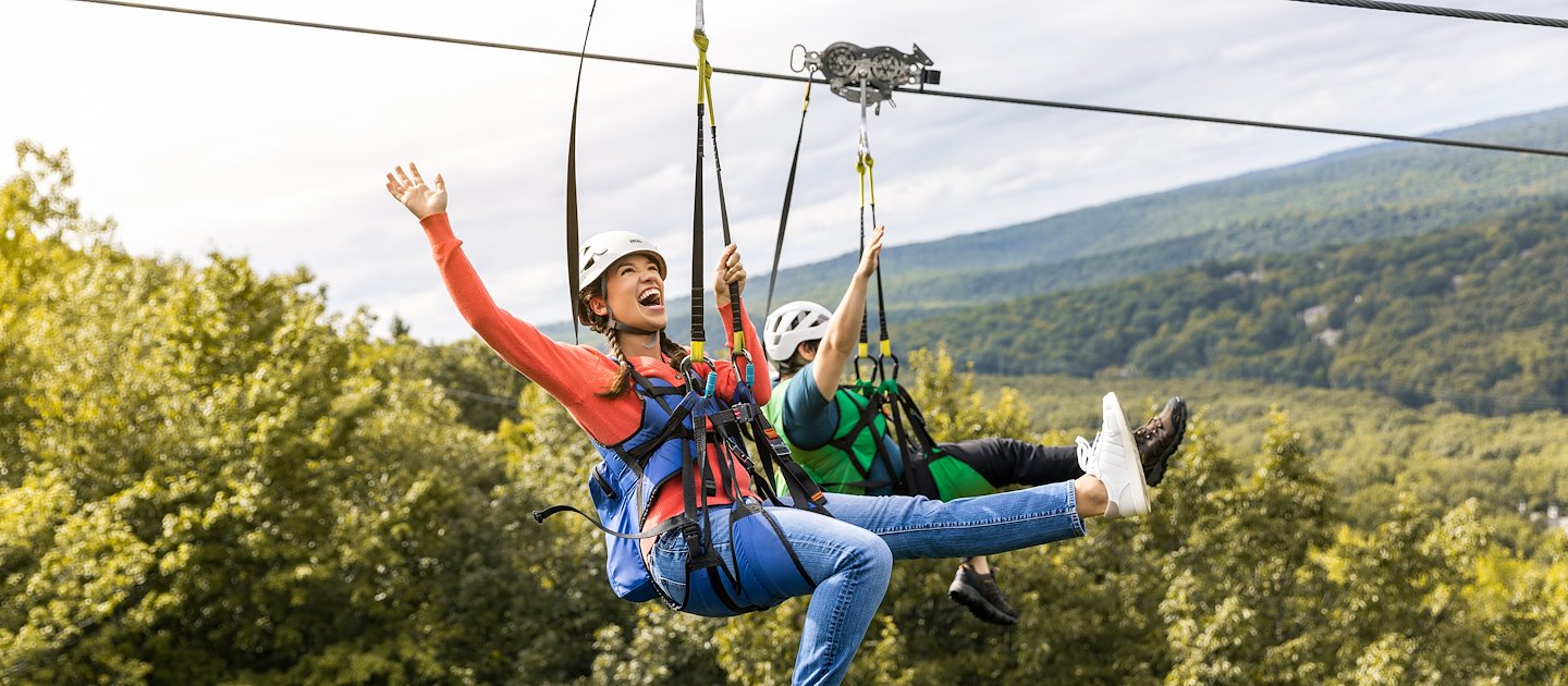 Young woman ziplining through the forest at Camelback Resort