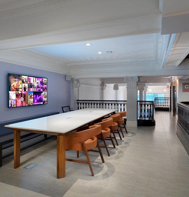 A large meeting room with a long table, chairs, and a TV on the wall.