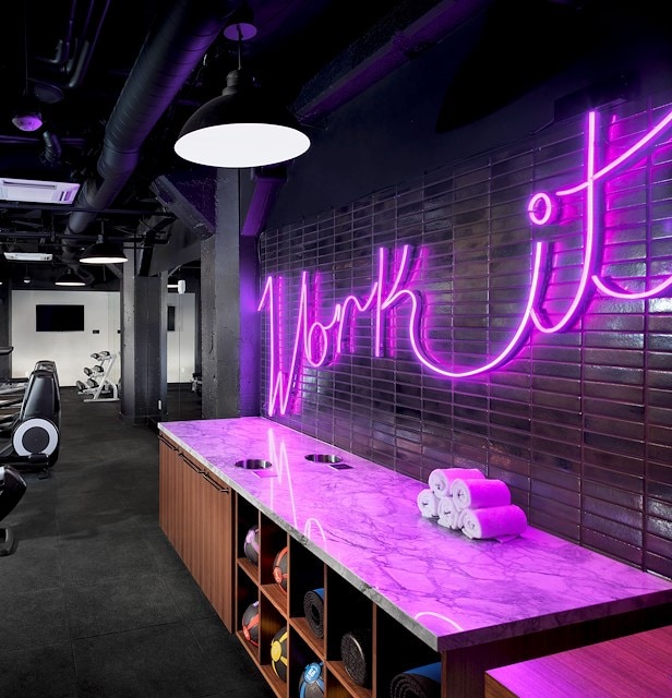 A modern gym with a purple neon sign, marble counter, and exercise balls.