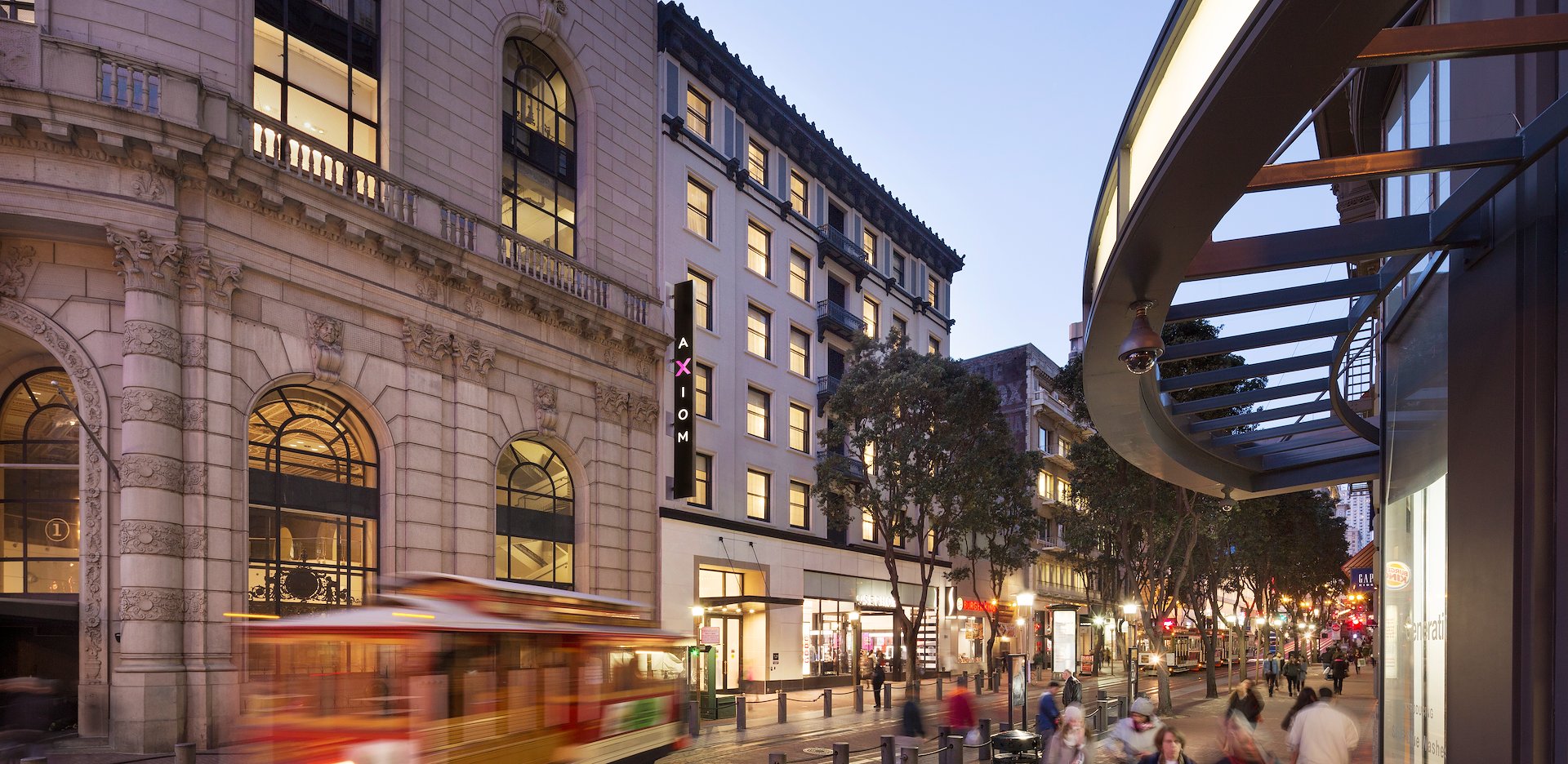Exterior view of Axiom Hotel with a classic San Francisco streetcar passing by along Powell Street.