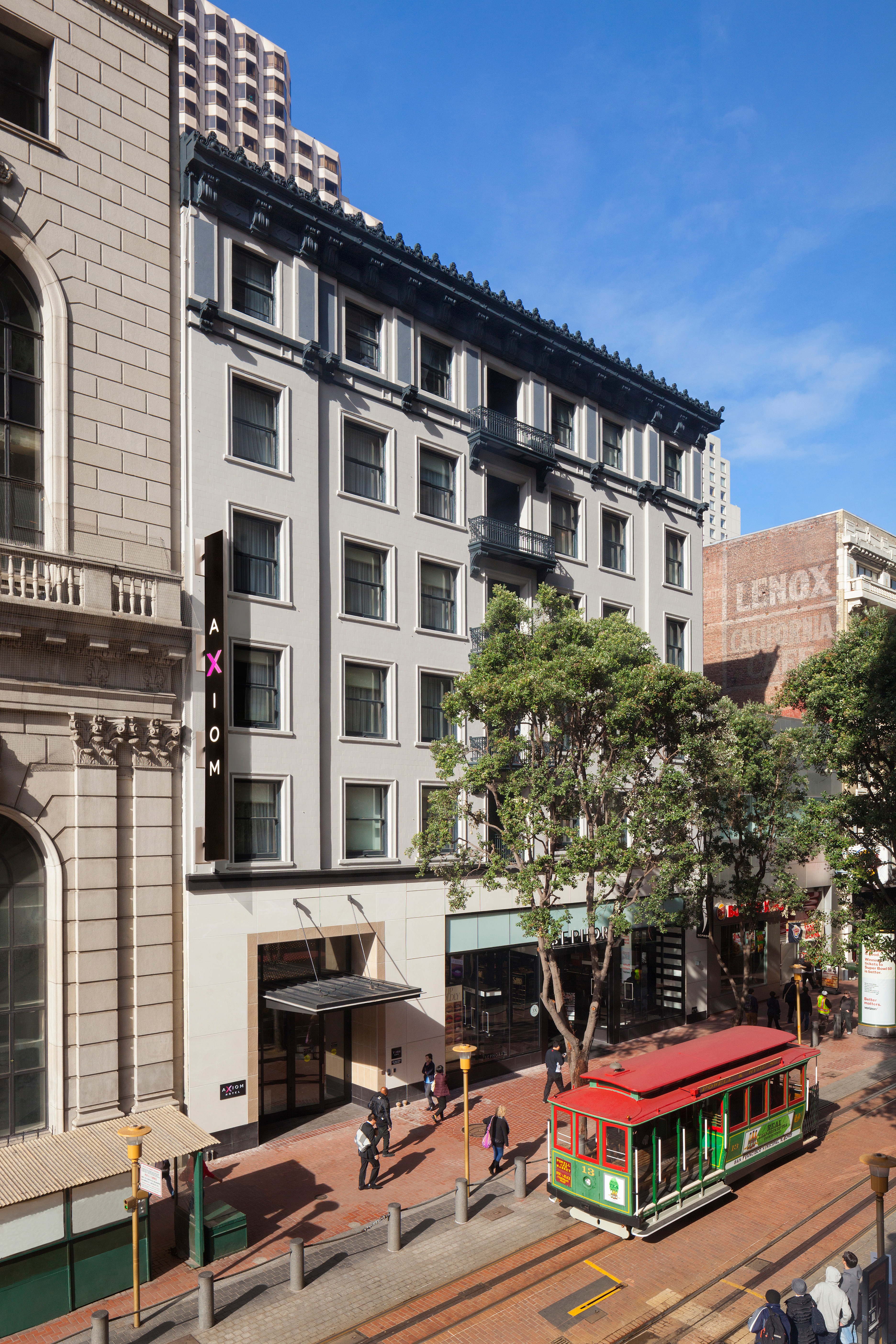 A multi-story building with a sign reading 'Axiom' and a trolley on the street in front of it.