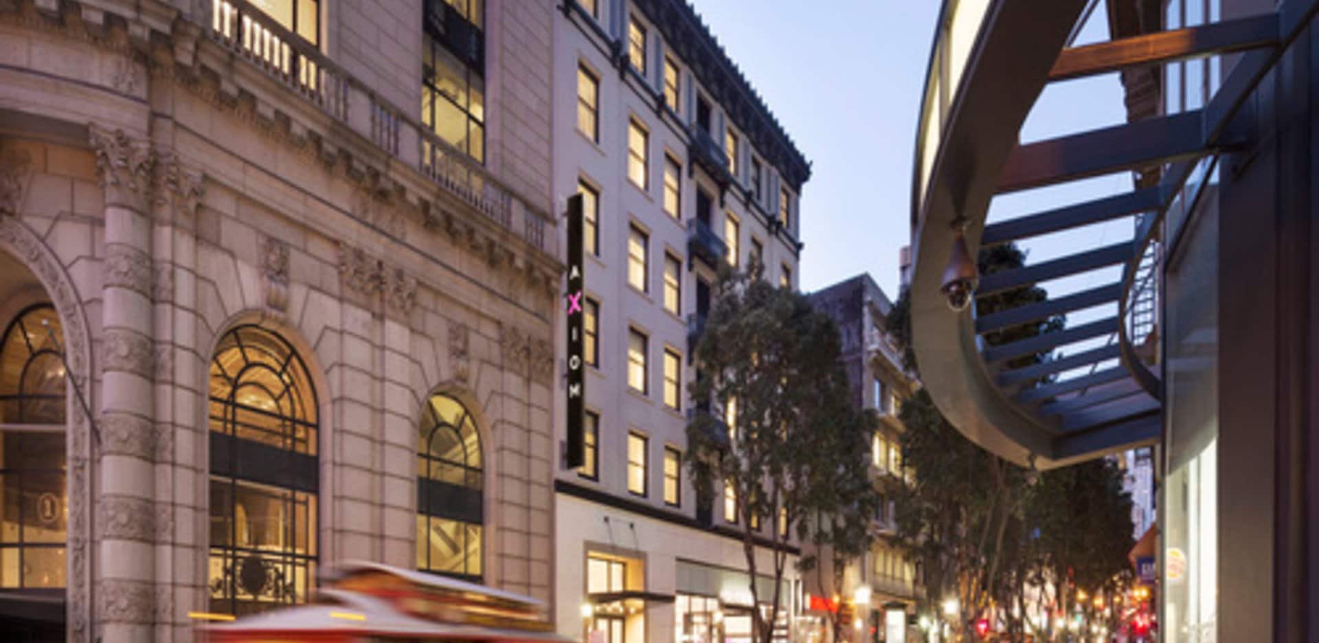 Exterior view of Axiom Hotel with a classic San Francisco streetcar passing by along Powell Street.