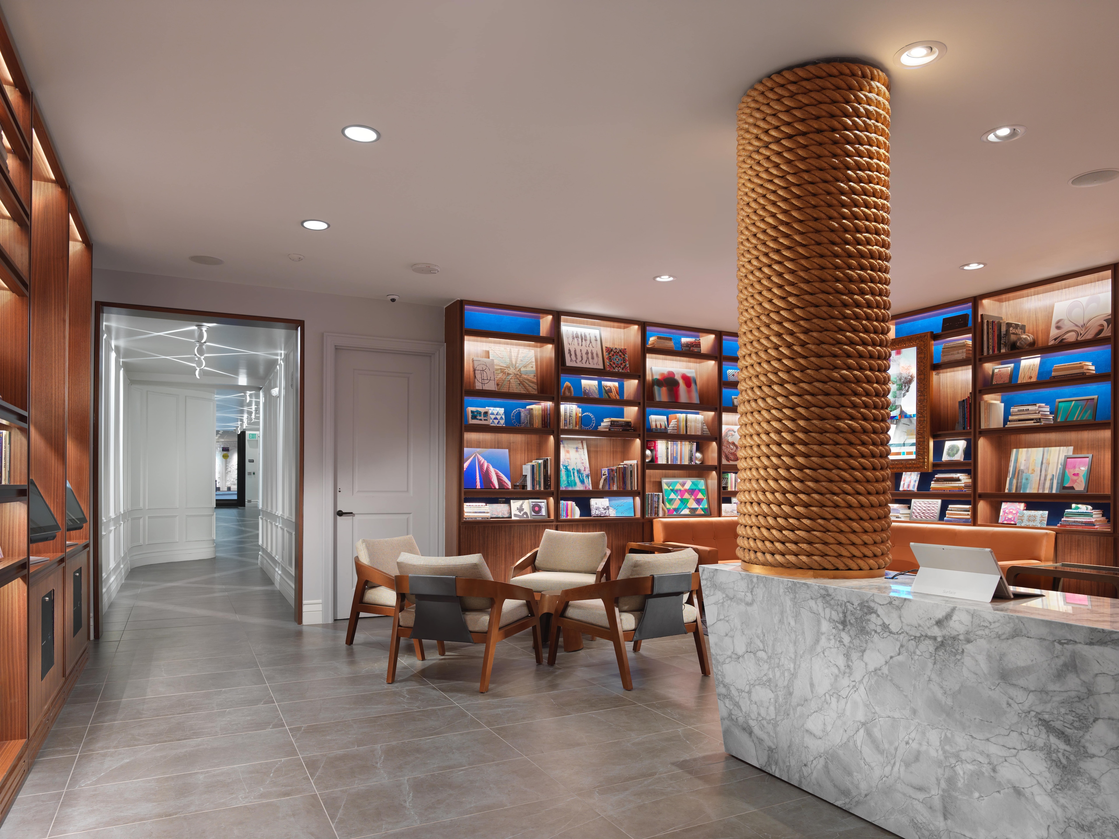 A lobby with a marble counter, bookshelves, and a seating area.