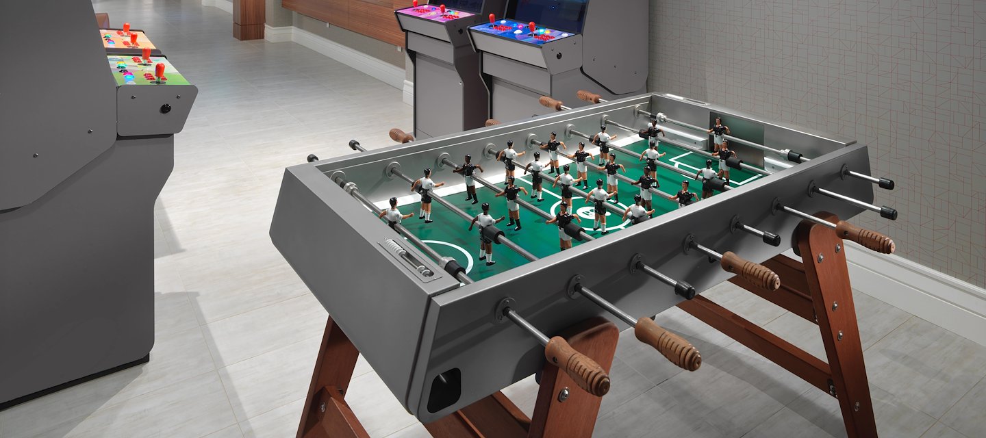 A foosball table with arcade games in the background