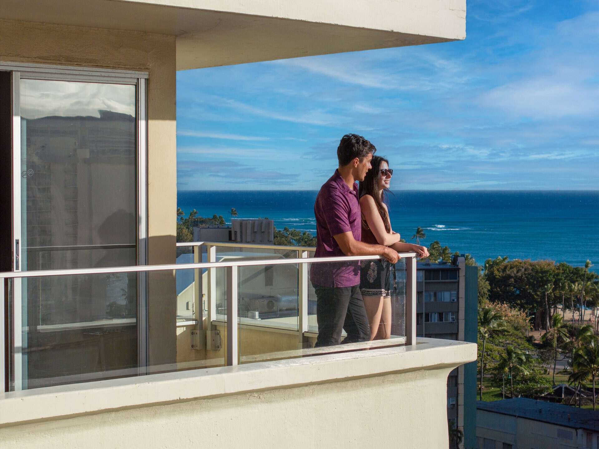 a man and woman standing on a balcony overlooking the ocean