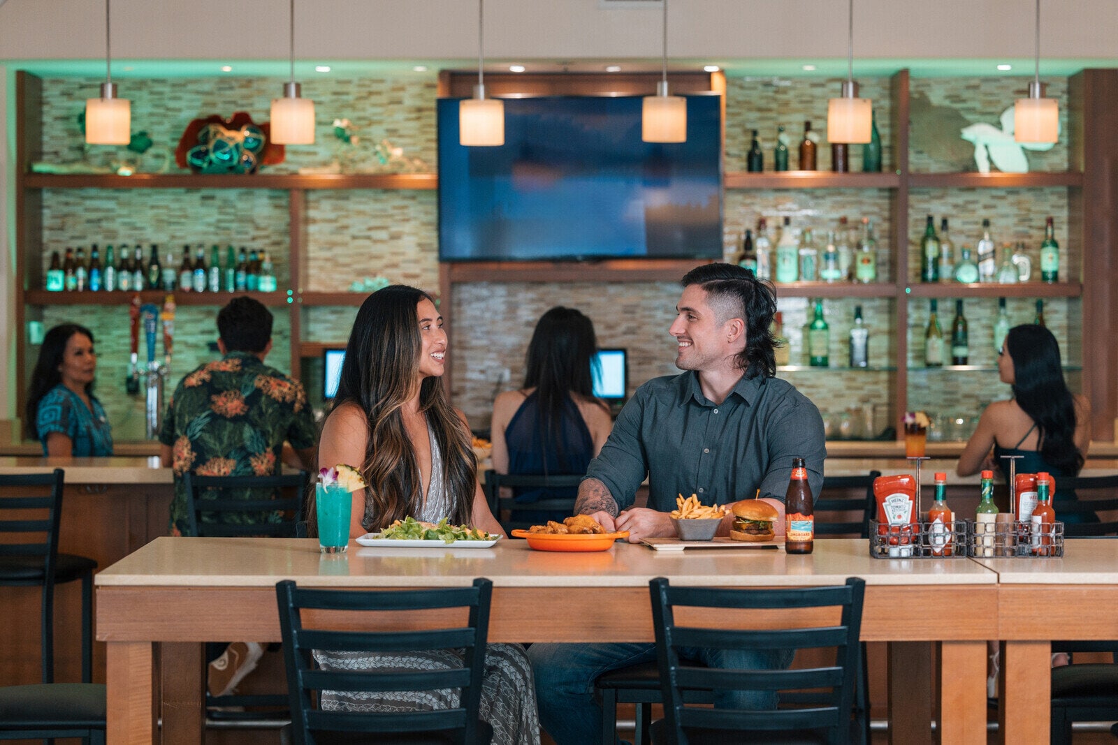 a man and woman sitting at a table with food and drinks