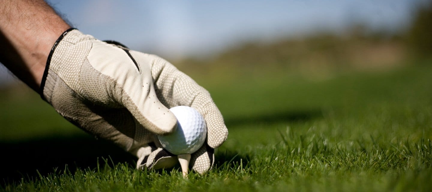 person setting golf ball on a tee