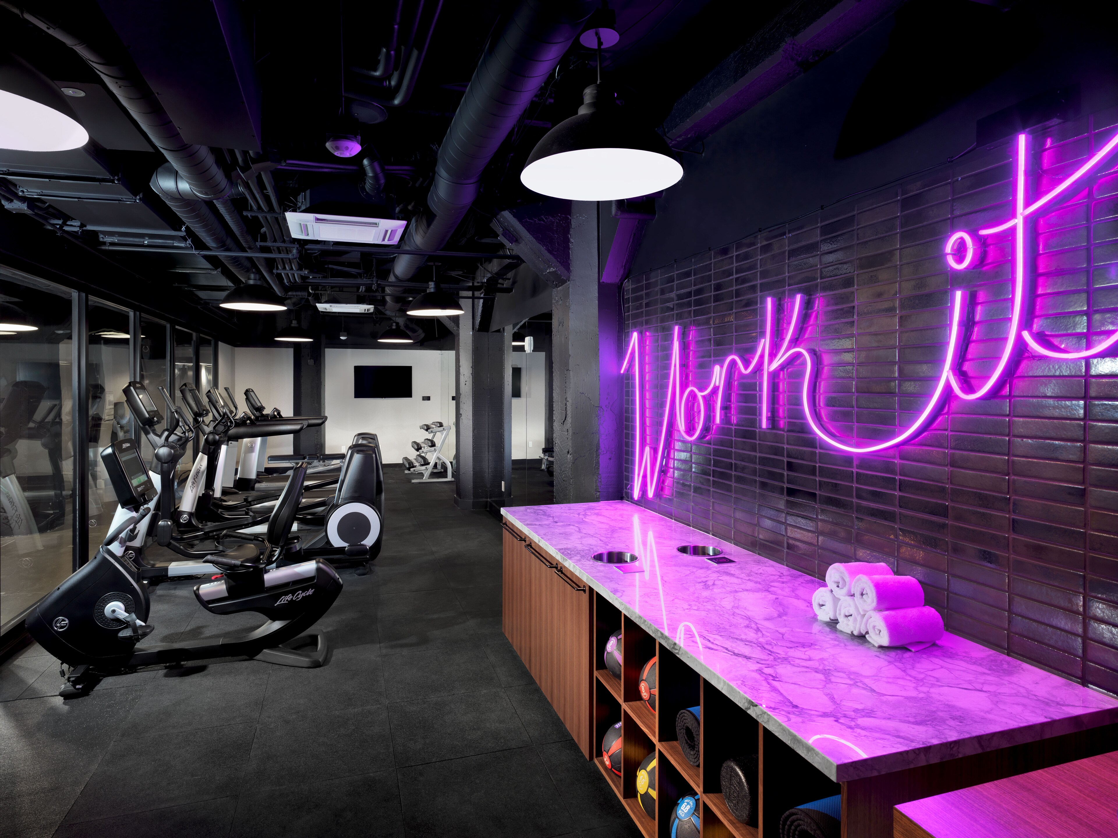 Fitness center at The Axiom Hotel features modern equipment and vibrant decor.