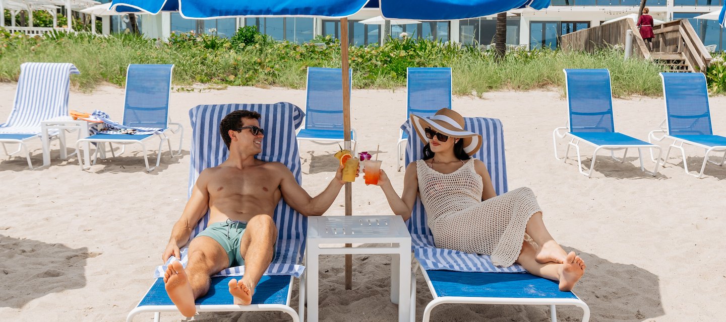Couple enjoying cocktails at Tideline Resort Spas beach chairs
