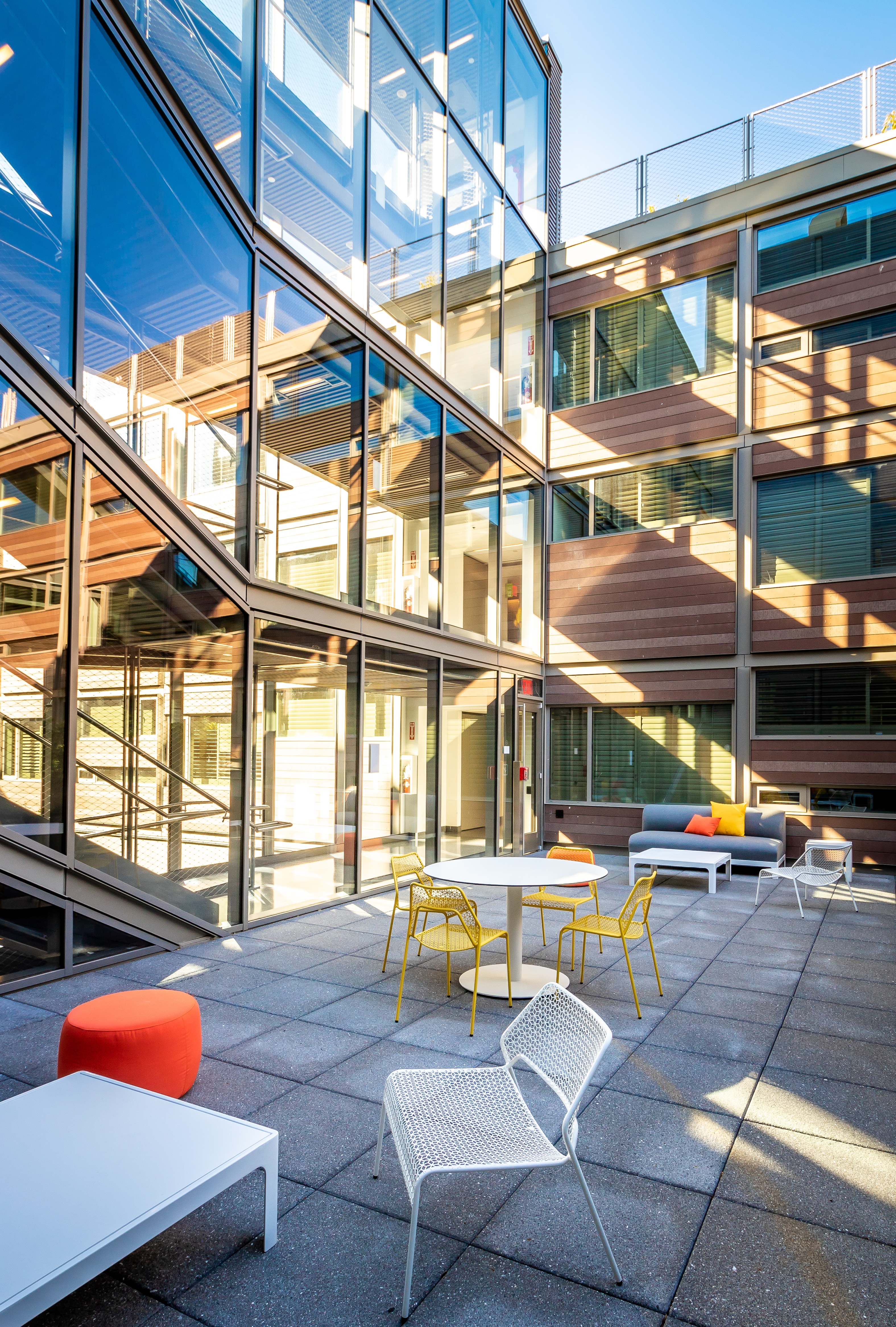 A modern building with a glass wall and staircase, featuring a seating area with a couch and coffee table.