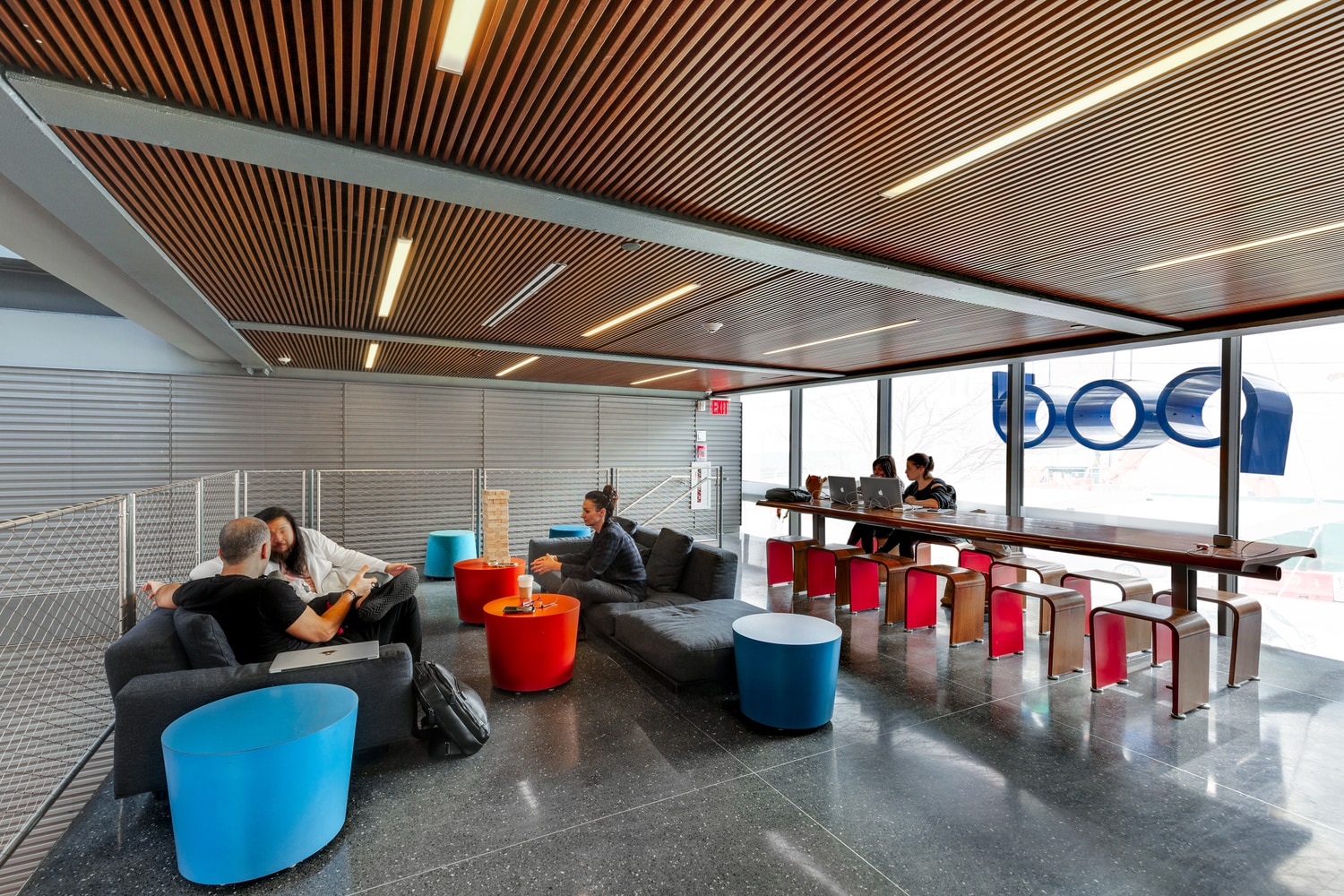 A modern lobby with people sitting on sofas and working at desks.