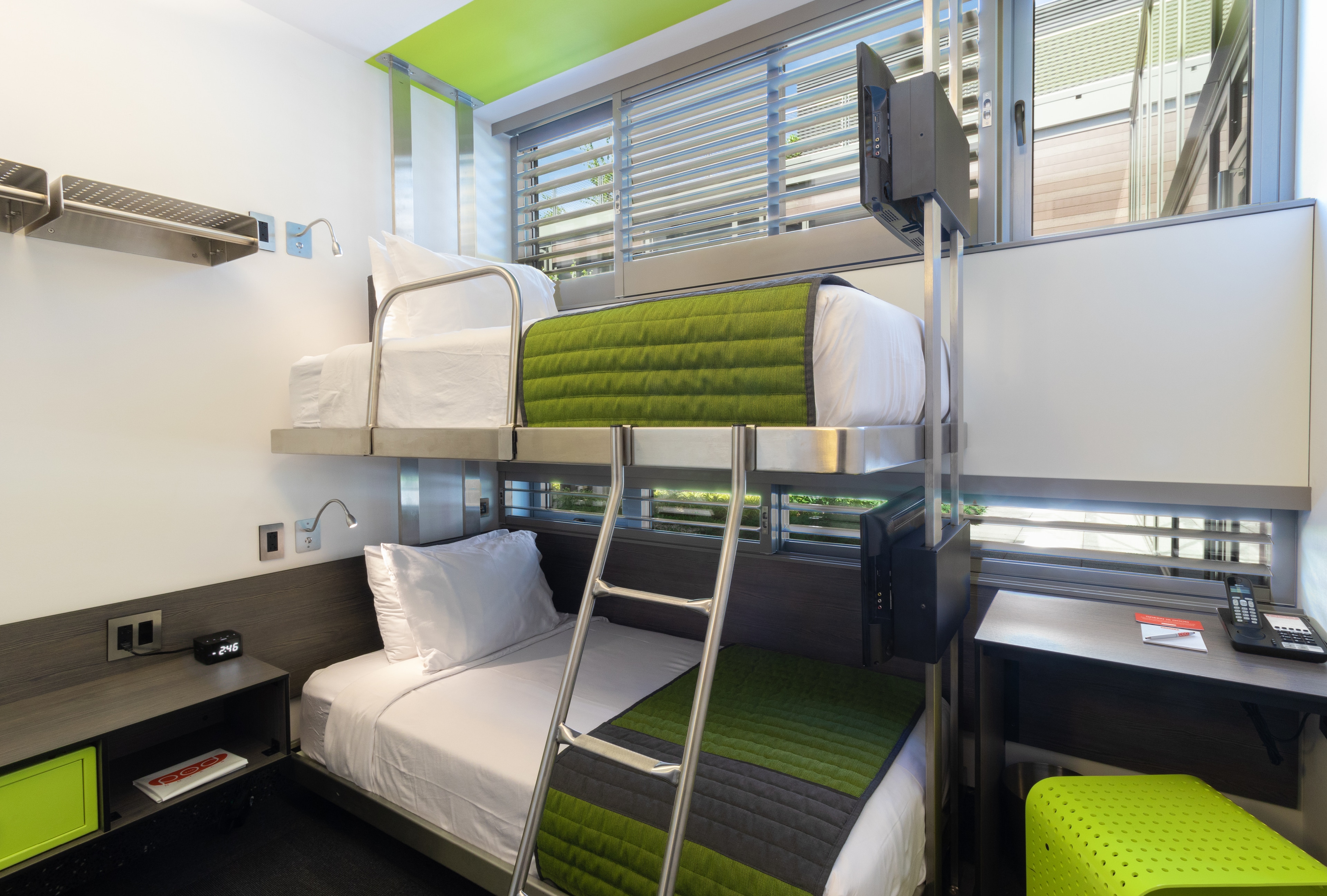A bunk bed with green bedding and a window in the background