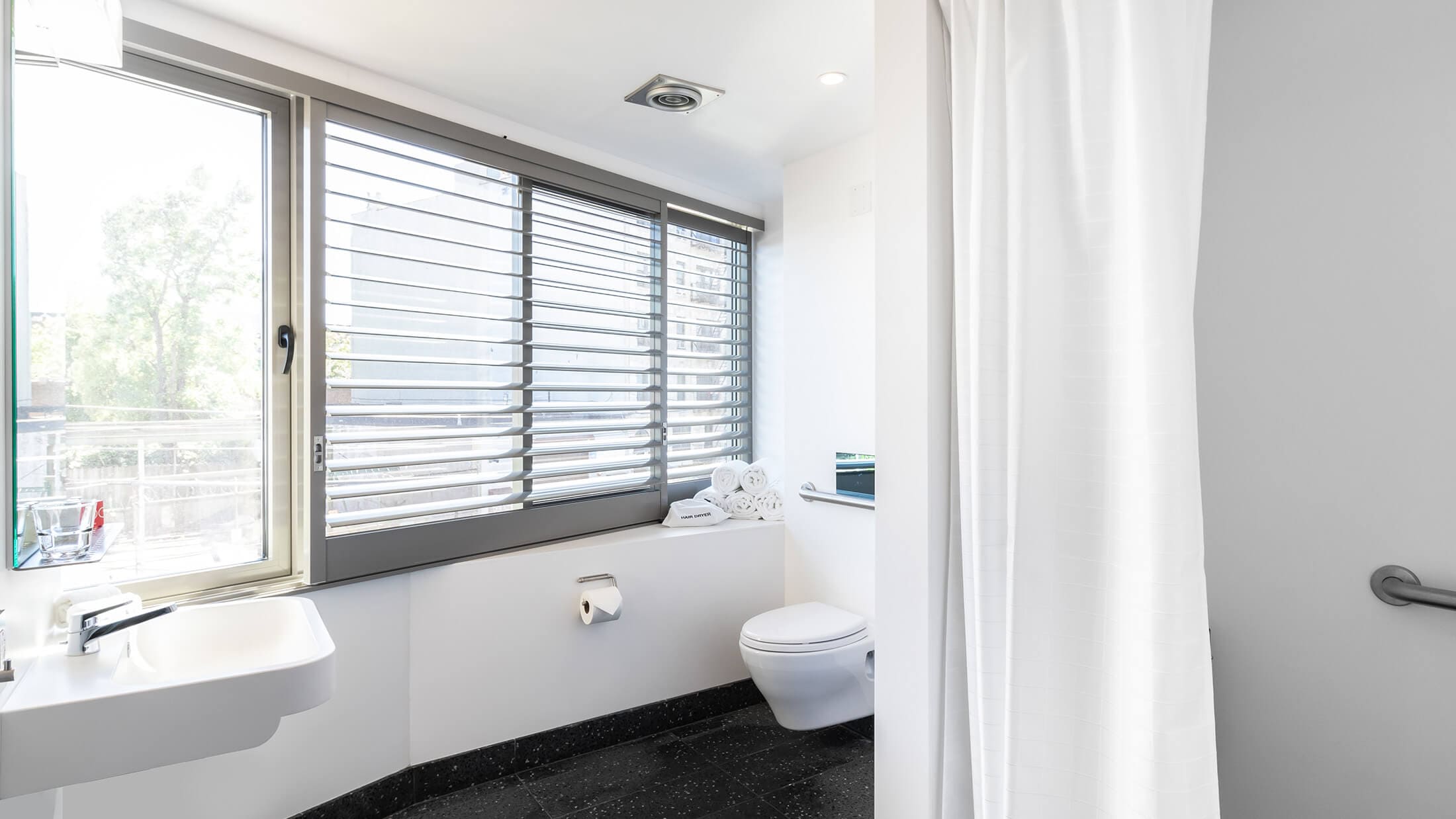 A clean bathroom with a toilet, sink, and window