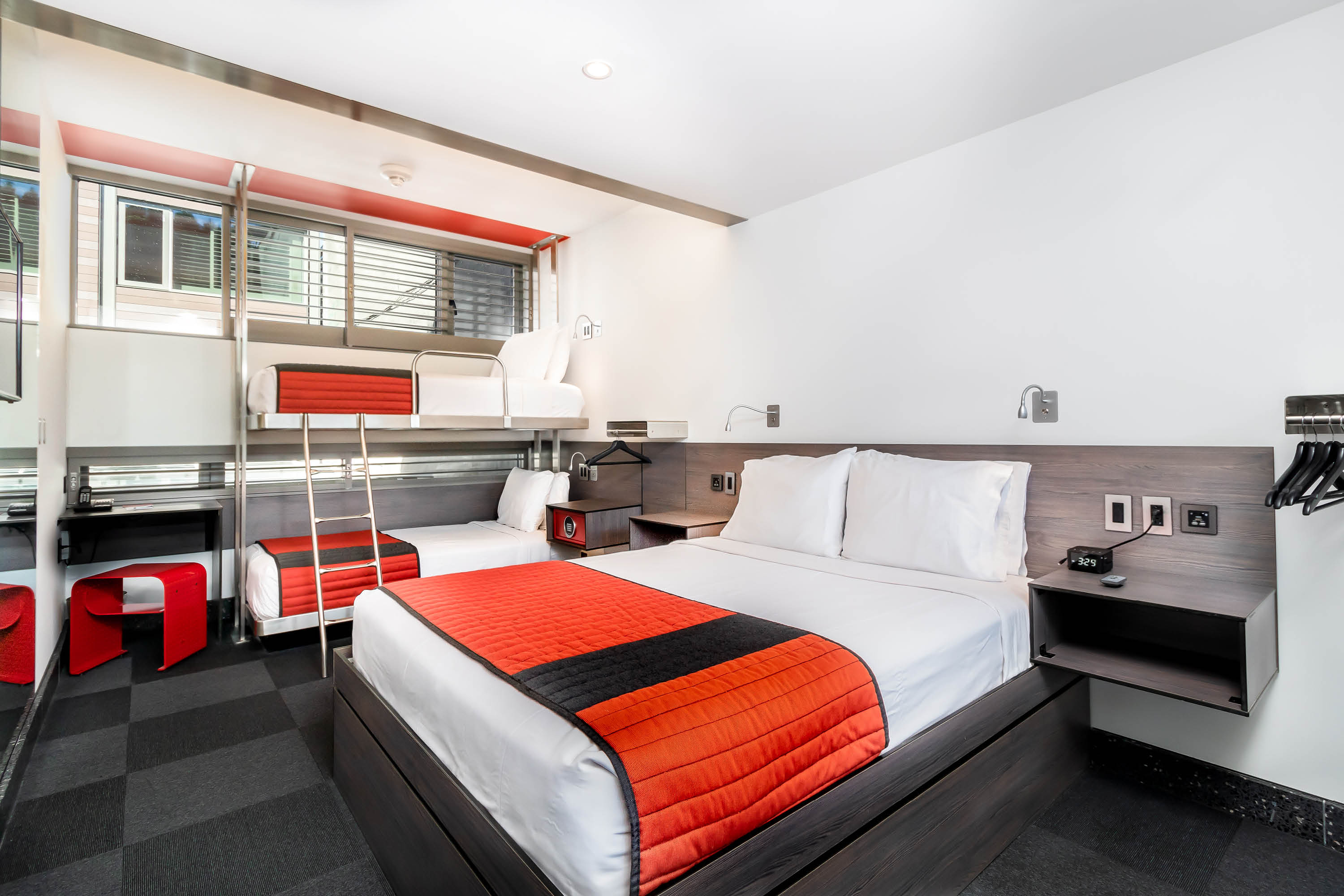 A hotel room with two beds, a window, and modern furnishings.