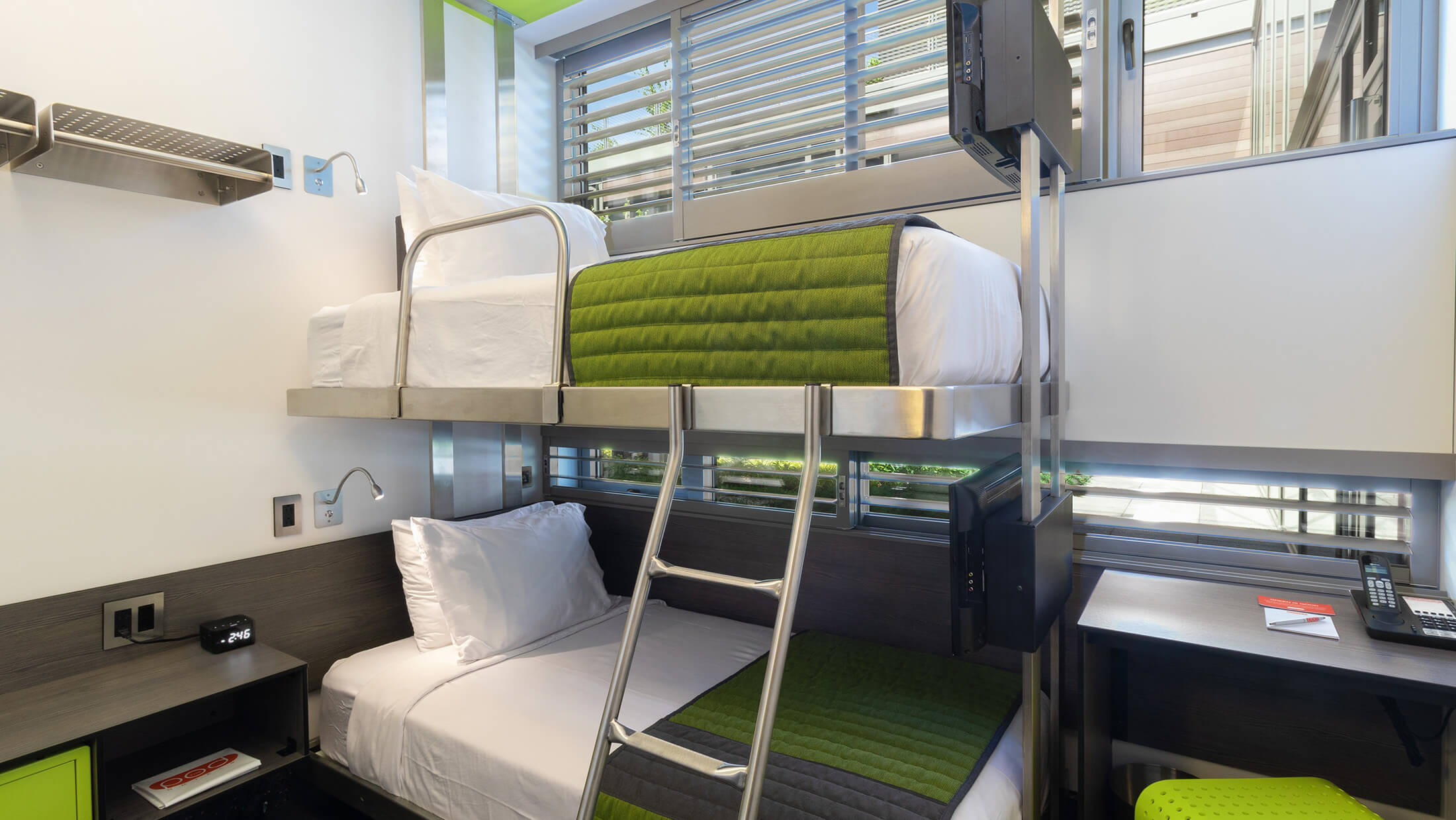 A room with a bunk bed, desk, and window