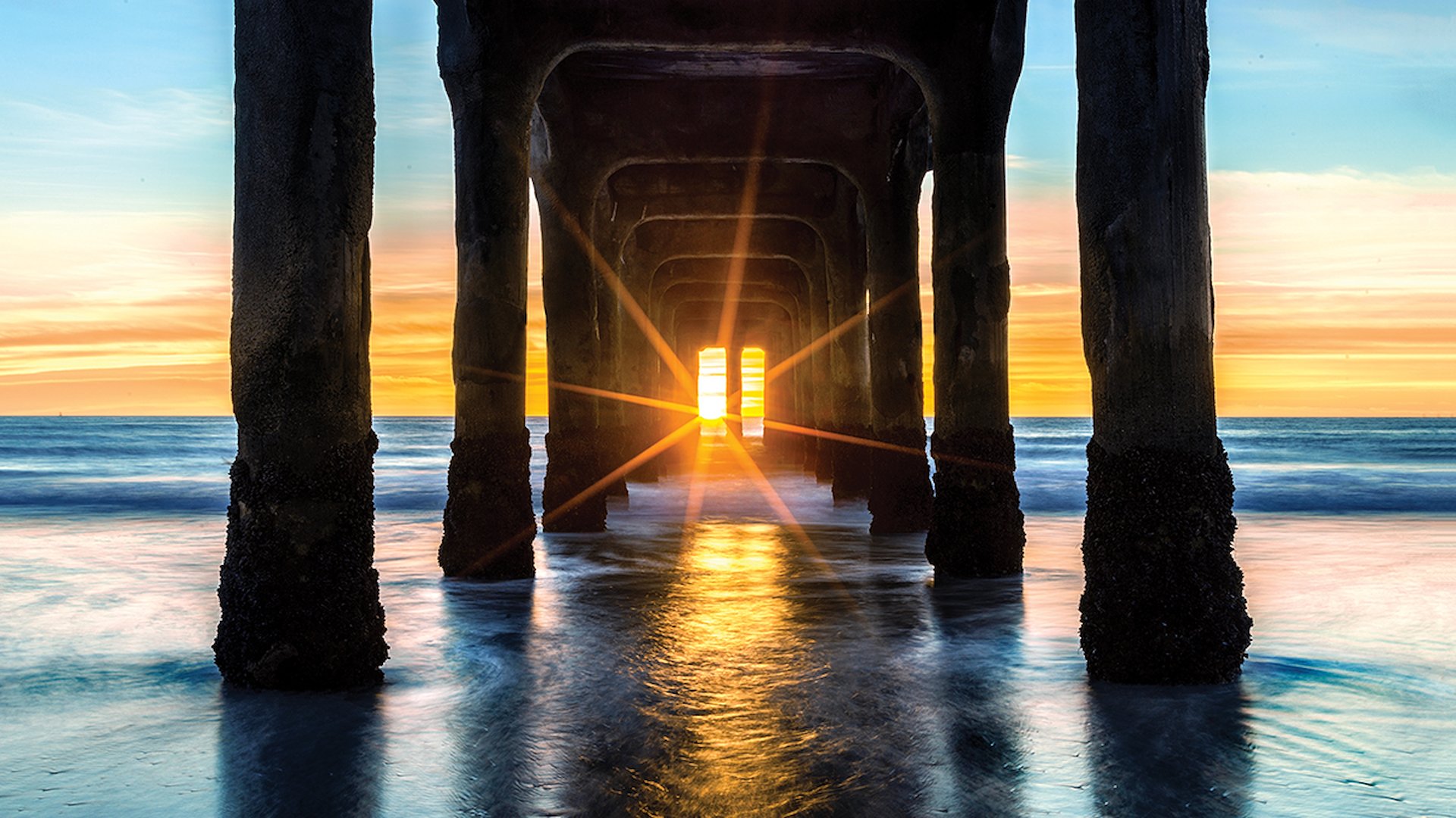 The stunning sunset shines beneath Manhattan Beach Pier.