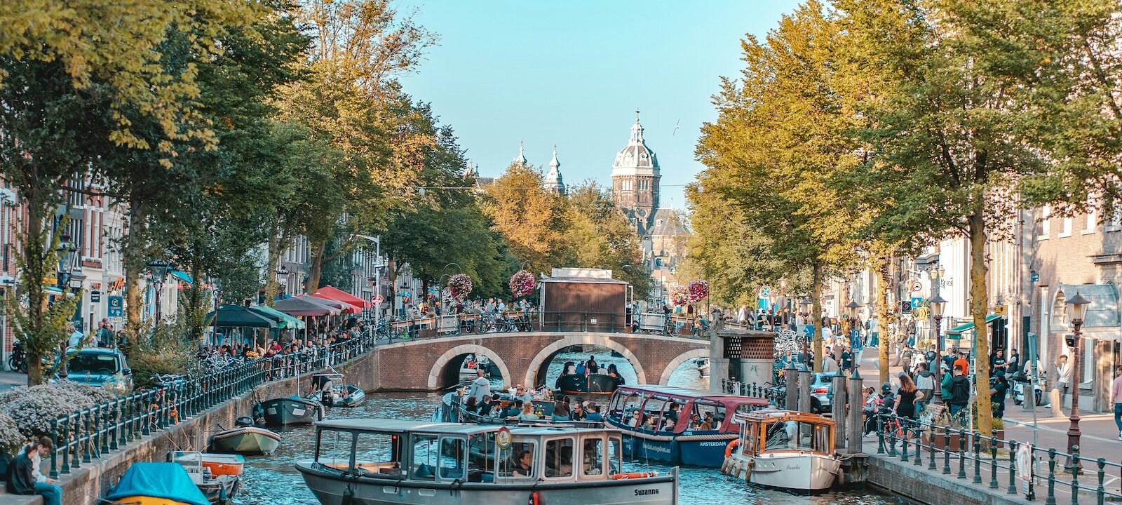 A canal filled with several boats and surrounded by pedestrians.