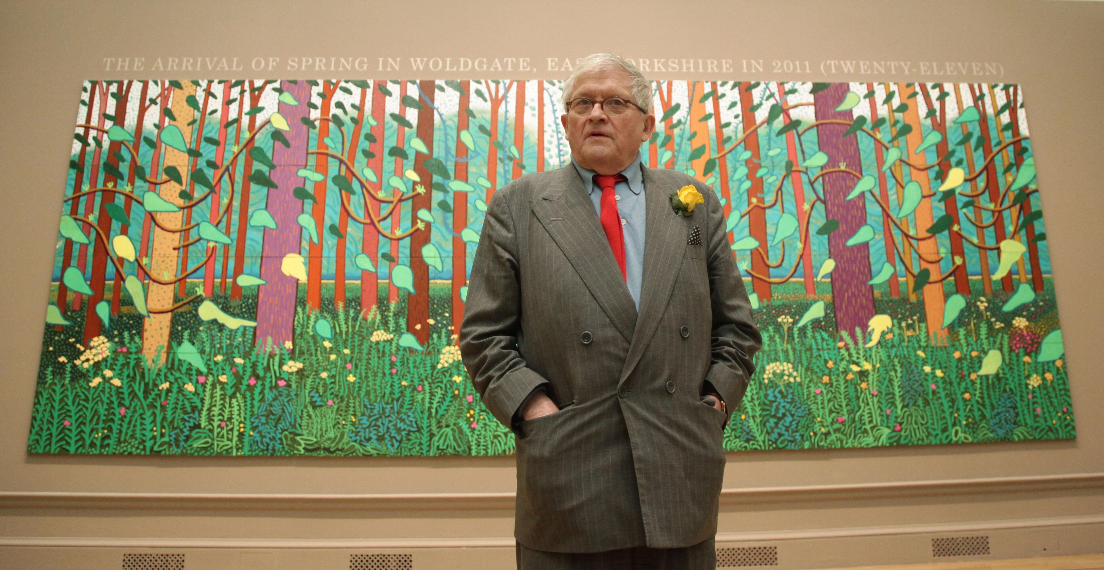 <p>David Hockney stands before his painting <i>The Arrival of Spring in Woldgate, East Yorkshire in 2011 (Twenty-Eleven)</i>.</p>