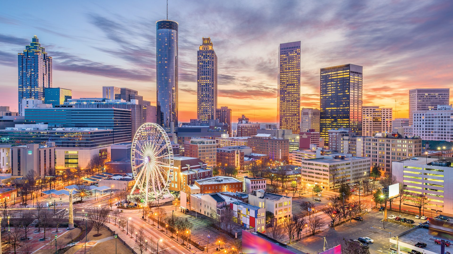 Downtown Atlanta’s historic landmarks and modern buildings glow with color at dusk.