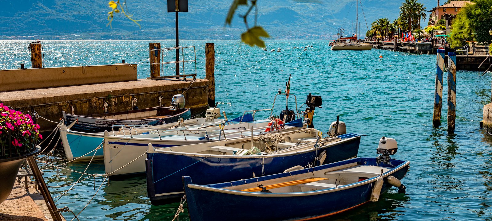 Boats moored on the glistening water of the Harbor of Limone, on the western bank of Lake Garda.