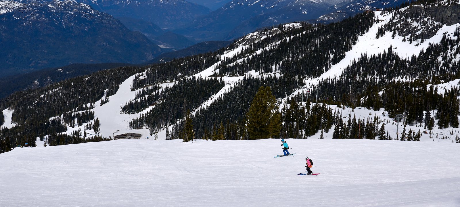 Skiers in Whistler traversing along stunning mountain views.