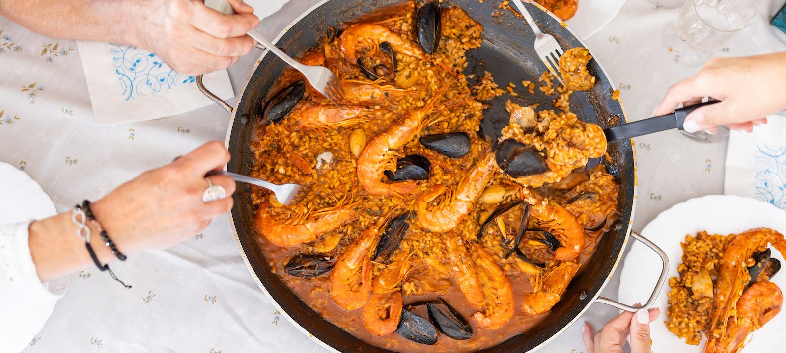 A group of friends share a delicious Spanish paella with prawns and mussels.